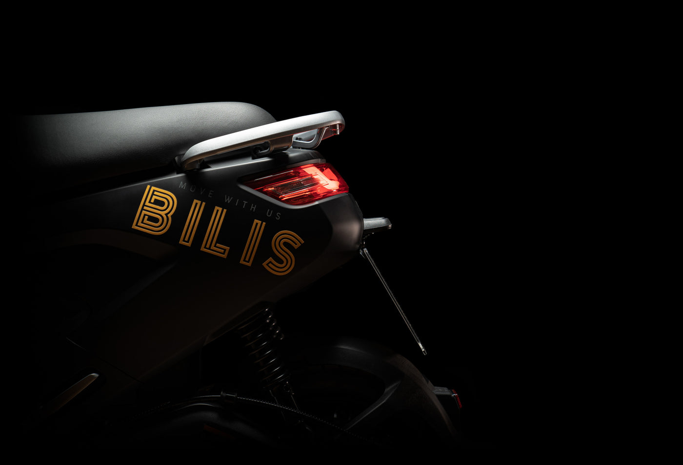 Rear of Bilis Electric Moped with reflective gold graphics of brand name and red LEDs on dark background